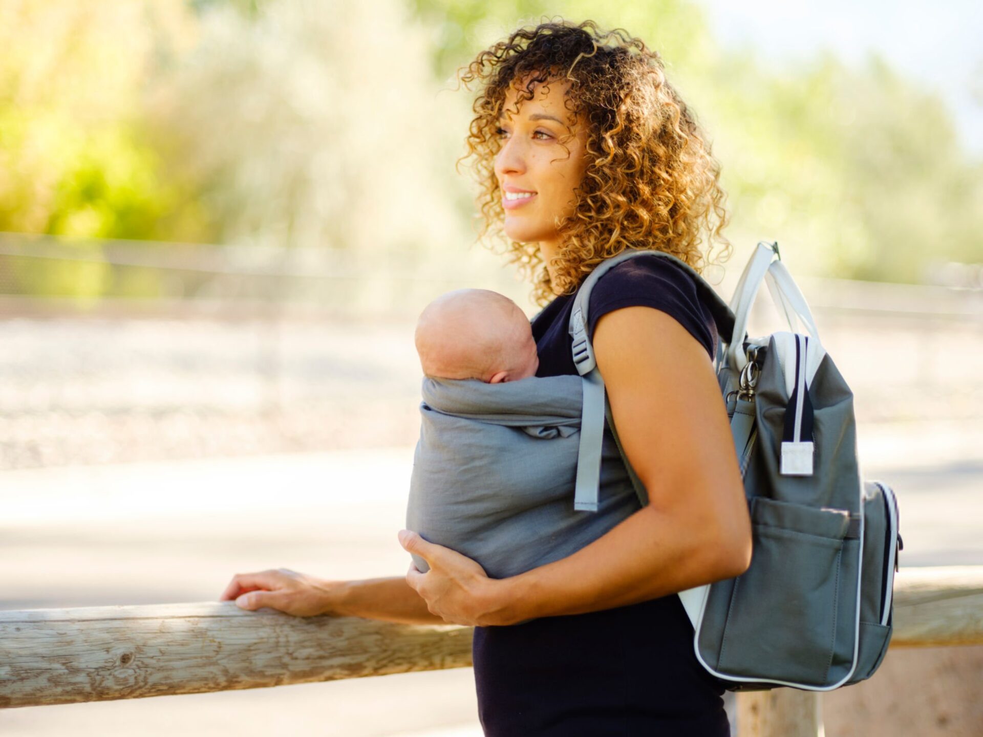 mamma con neonato nella fascia mentre fa attività alla'aperto