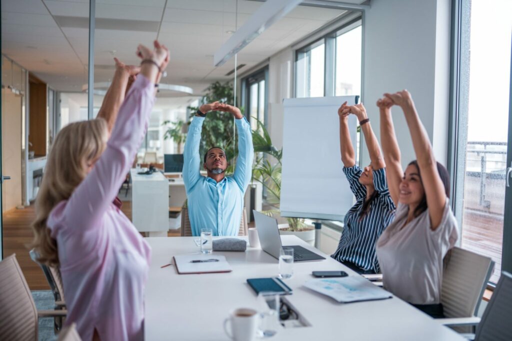 colleghi durante riunione fanno pausa per fare stretching per la postura