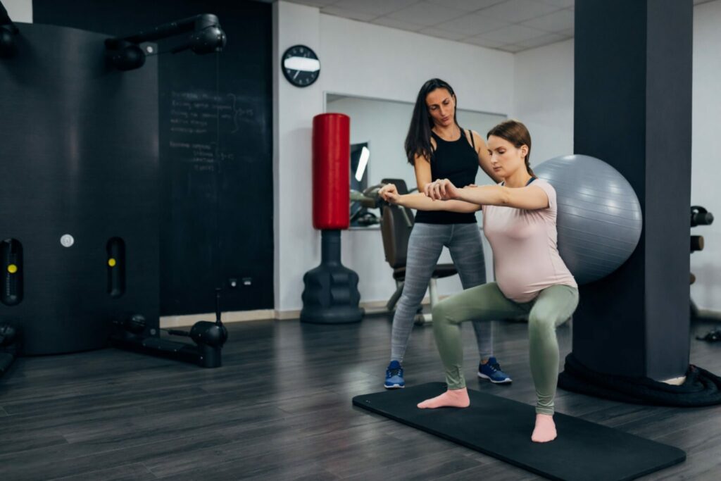 donna incinta fa squat in palestra con aiuto